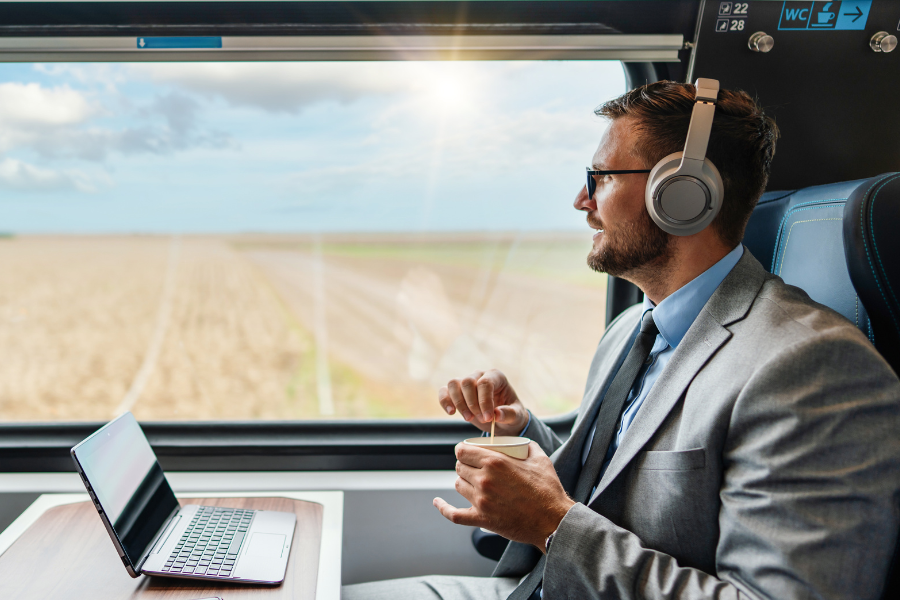 MBA Student mit Laptop im Zug beim Lernen mit Kopfhörern