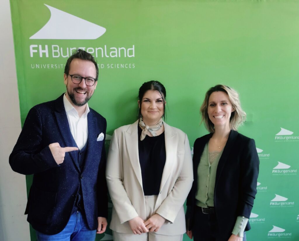 Michael Roither, Julia Gottesheim und Anria Brandstätter nach der Master-Abschluss Prüfung vor der Leinwand der FH Burgenland