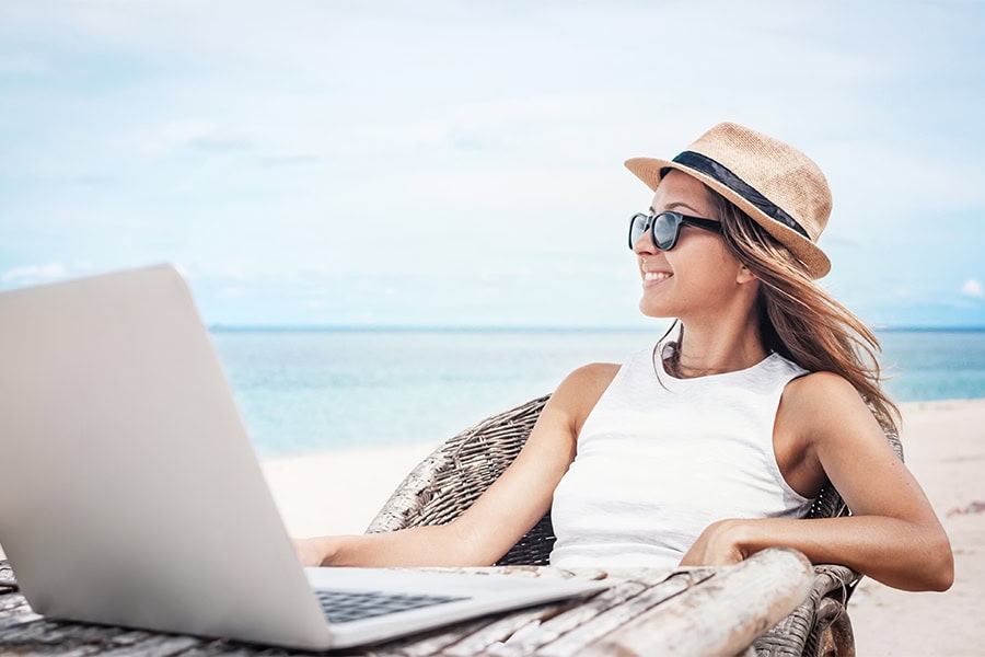 Studentin mit Laptop am Strand beim Studieren beim besten Fernstudienanbieter