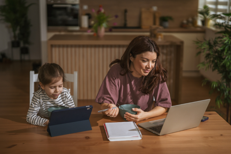 flexibel-lernen-und-fernstudium-vor-september-starten Frau mit Kind am Tisch mit Tablet und Laptop beim Spielen und Lernen